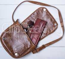 open brown leather bag with purse and glasses