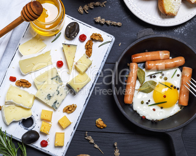 fried eggs with sausages in a round black cast-iron frying pan