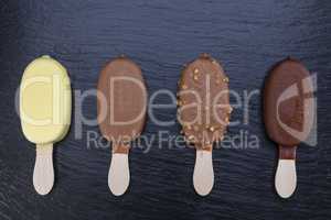 Ice cream on stick covered with chocolate on black slate