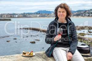 Woman enjoys vacation by the sea with wine and tapas