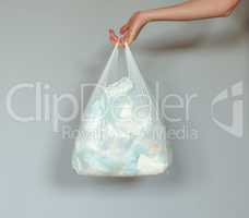 Woman hand holding a plastic bag full of dirty used baby diapers