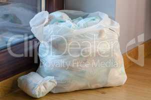 a bag full of dirty baby's diapers standing on the floor side