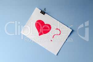 The painted red heart with ? on white paper sheet