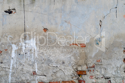 old grey concrete garage wall with red bricks, cracks and white