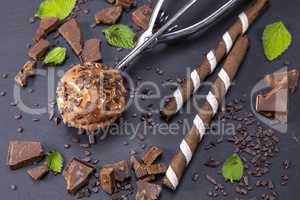 Chocolate ice cream in scoop on black slate