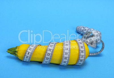 yellow raw zucchini wrapped in a measuring tape
