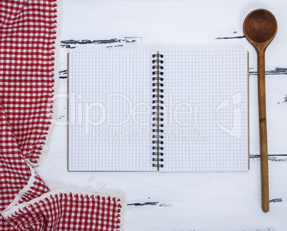 notebook with white sheets and a kitchen wooden spoon