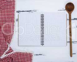 notebook with white sheets and a kitchen wooden spoon