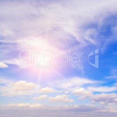 Sun on blue sky with white clouds.