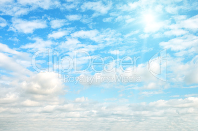 Sun on blue sky with white clouds.