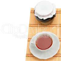 Cup of tea and jam jar isolated on white background. Free space