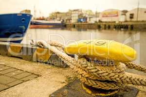 bollard with mooring line and blue ship hull