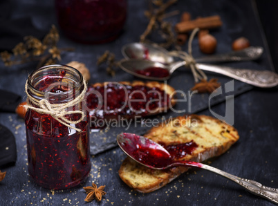 glass jar with raspberry jam and a slice of bread
