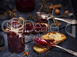 glass jar with raspberry jam and a slice of bread