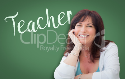 Teacher Written On Green Chalkboard Behind Smiling Middle Aged W