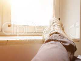 Feet crossed in front of a closed window