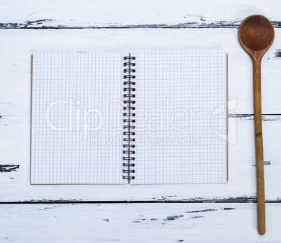 open empty notebook in a box and a kitchen spoon