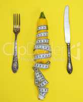 yellow zucchini wrapped in a measuring tape and an iron fork wit