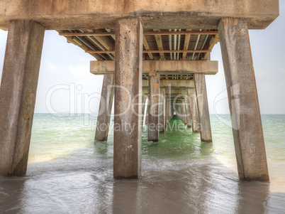 Under the Naples Pier with a blue sky above in the summer