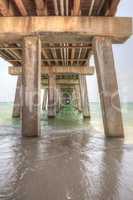 Under the Naples Pier with a blue sky above in the summer