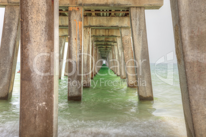 Under the Naples Pier with a blue sky above in the summer