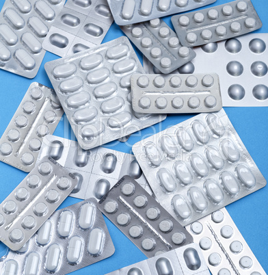 different white tablets in a package are scattered on a blue bac