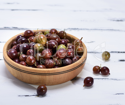 ripe red berries of gooseberries in a brown  bowl