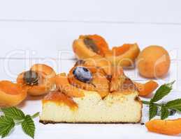 piece of cheesecake with apricots on a white wooden board