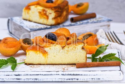 piece of cheesecake with apricots on a white wooden board