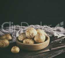 young potatoes in the peel lay in a wooden bowl