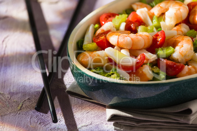 Close up of salad of shrimps and chopsticks