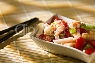 Shrimp salad over a bamboo tablecloth and chopsticks
