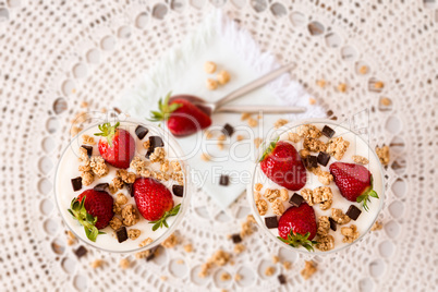 Strawberries cereals and chocolate flakes in two cups of plain y