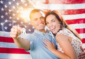 Military Couple Holding House Keys In Front of American Flag