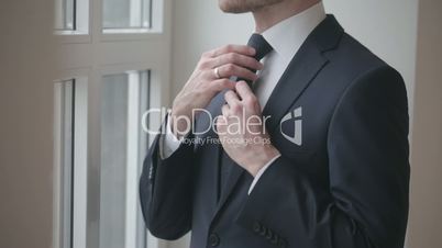 Man in black suit tying tie