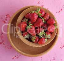 fresh ripe red strawberries in a brown wooden round plate
