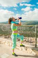 The girl after a long run drinks water from the thermos