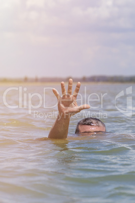 right man's hand gives a signal for help out of the water
