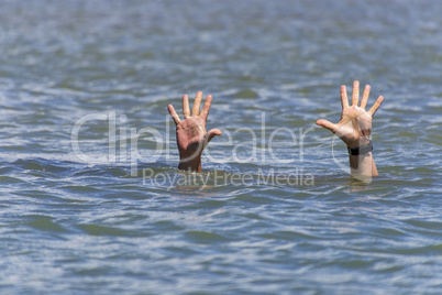 pair of masculine hands sticks out of the sea water