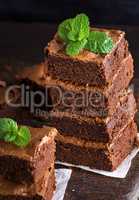 Baked square pieces of chocolate brownie pie are stacked