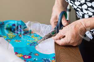 A woman cuts out a white fabric lining for a dress