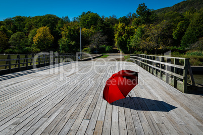 A large red umbrella on a wooden bridge.