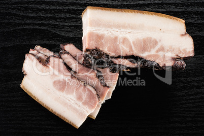 Fresh smoked english bacon on black wood