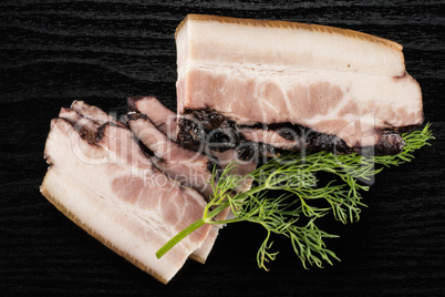 Fresh smoked english bacon on black wood