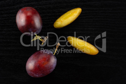 Fresh Raw vibrant plums on black wood