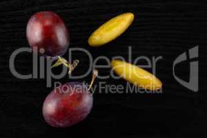 Fresh Raw vibrant plums on black wood