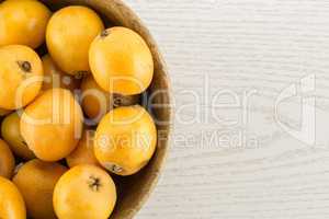 Fresh raw orange japanese loquat on grey wood