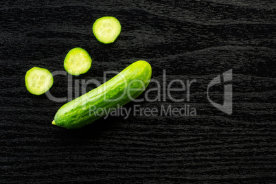 Fresh raw mini cucumber on black wood