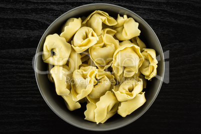 Fresh Raw tortellini pasta on black wood