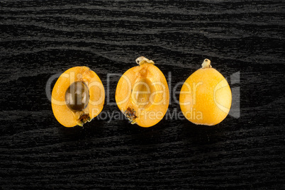 Fresh raw orange japanese loquat on black wood